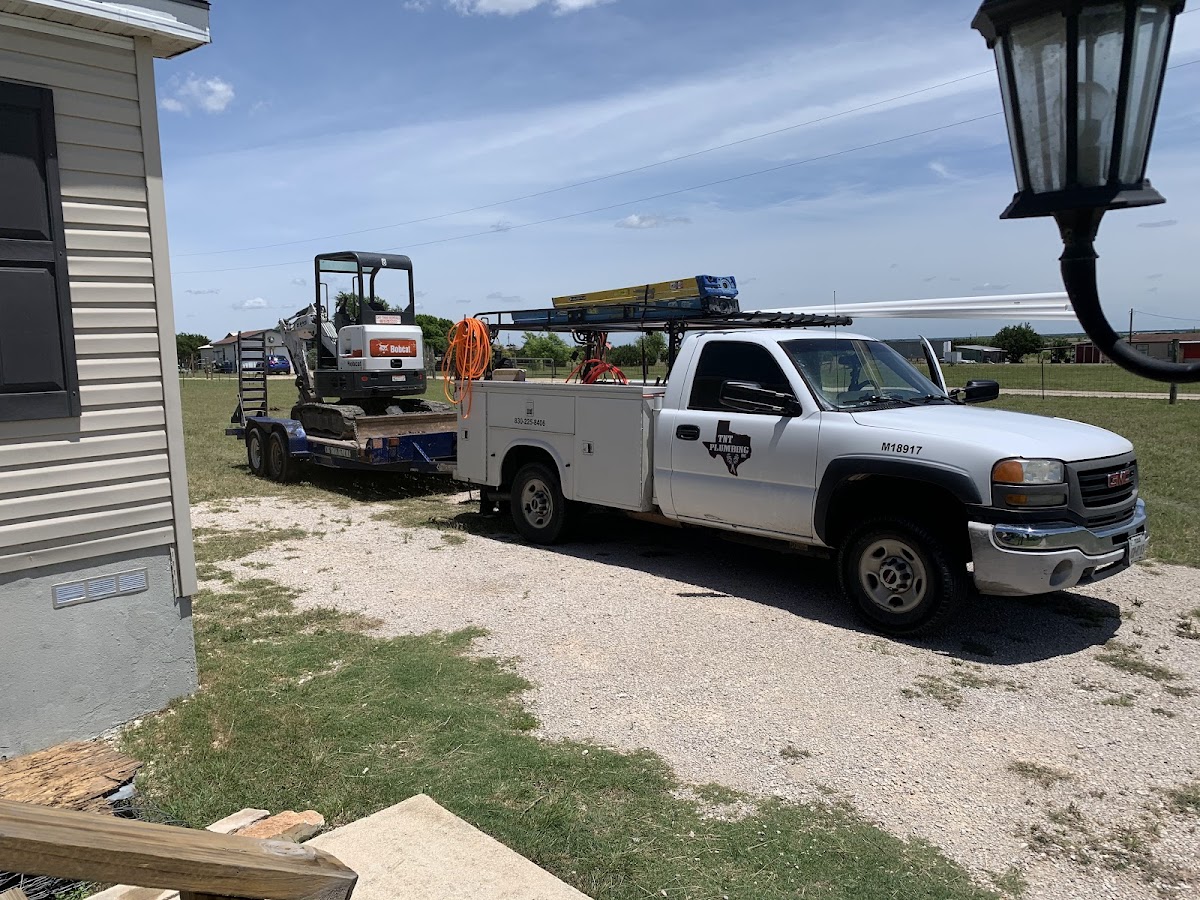 TNT Plumbing service truck with excavator at a Hill Country job site