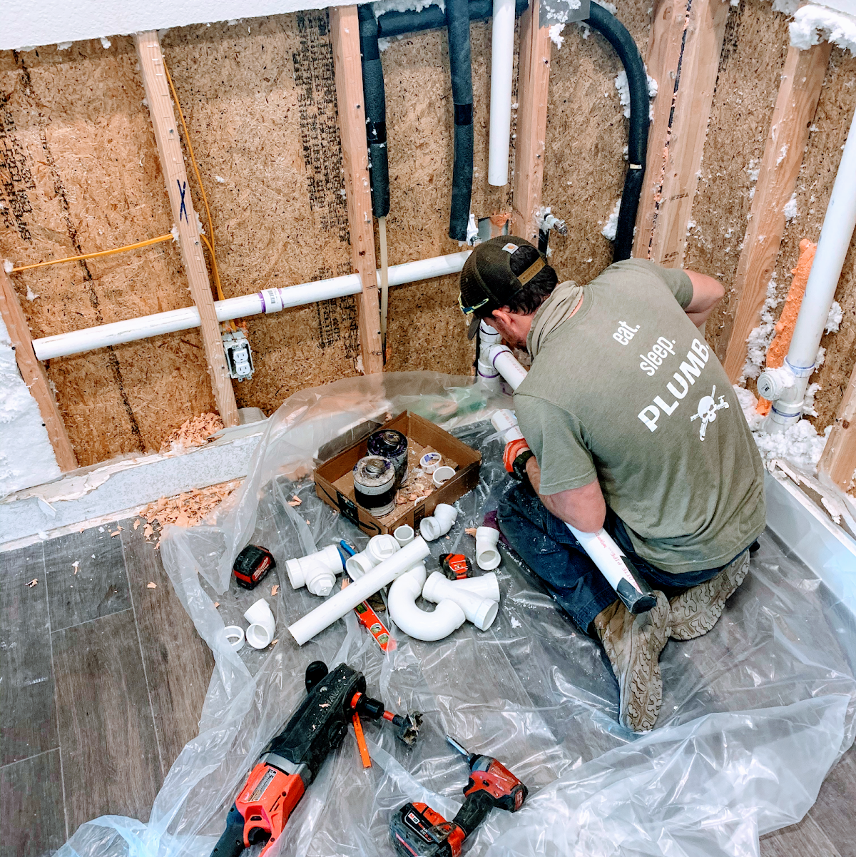 Plumber doing rough-in pipe work inside wall framing at a new construction site
