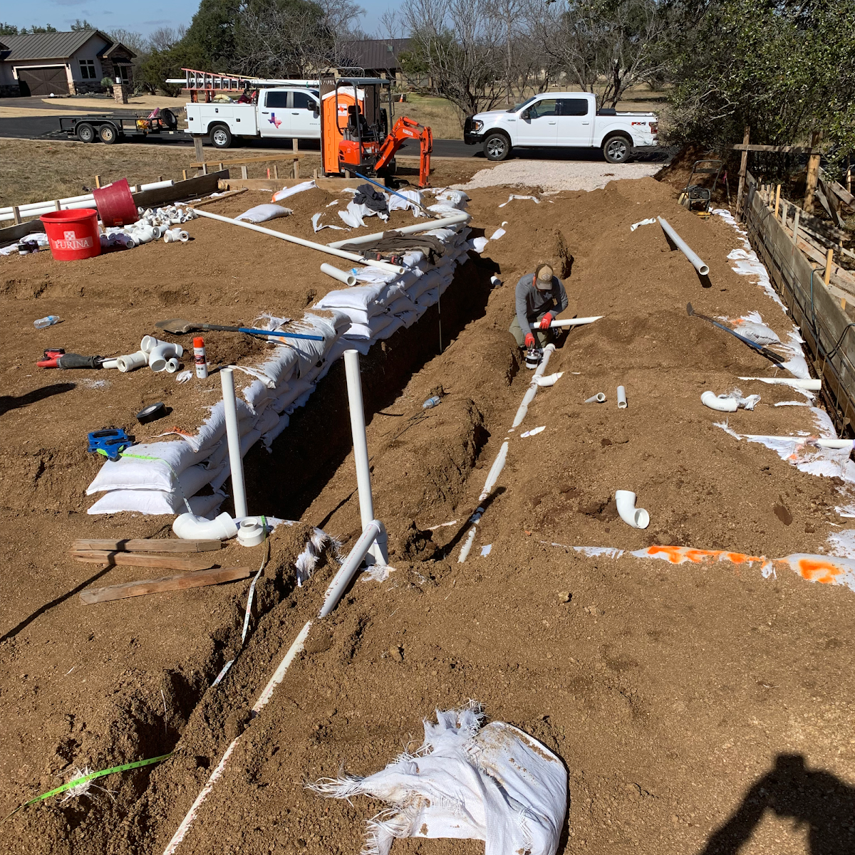 Large trench excavation for underground sewer line work with TNT trucks in background